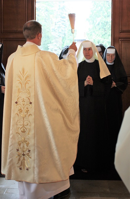 Father blesses the novice before professing her first vows
